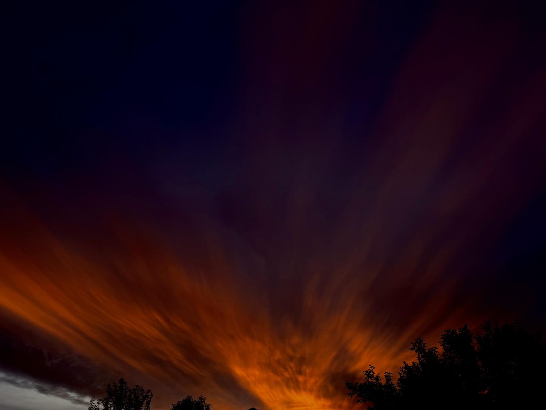 Flame colored clouds radiate from the impending rising sun.