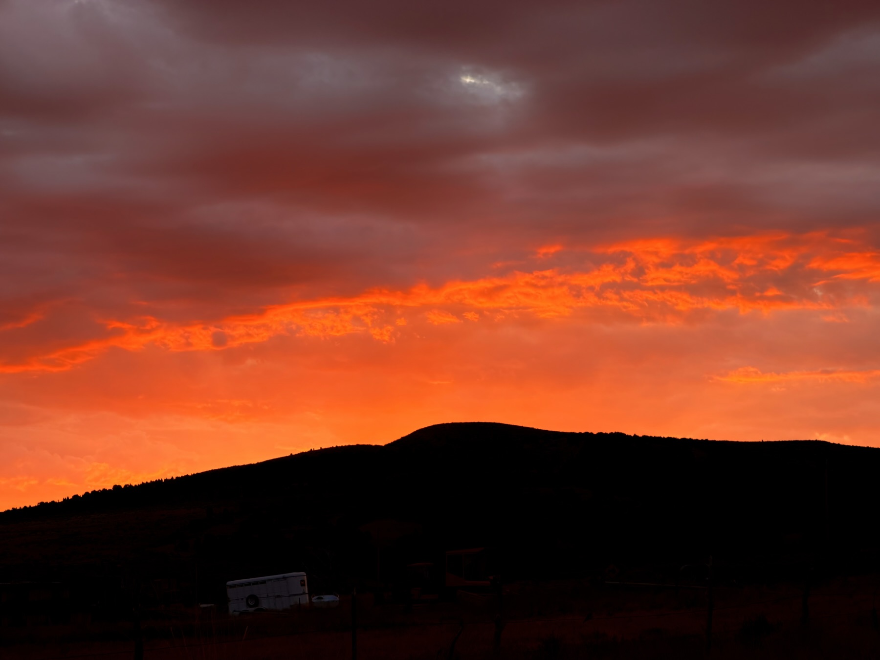 Vivid colors from a sunrise contrast against the darkness of a mountain.